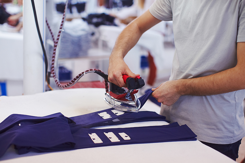 Man worker on factory iron ready for packaging produced cloth