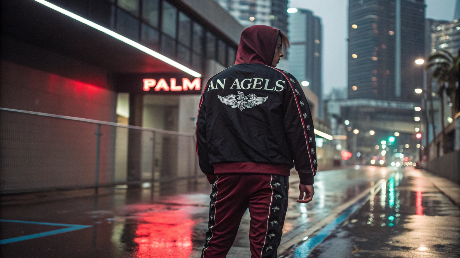 A model wearing a Palm Angels-inspired custom tracksuit with gothic typography, oversized fit, and bold color contrasts, standing in a neon-lit cityscape with wet pavement reflecting urban lights, capturing a high-fashion streetwear aesthetic.